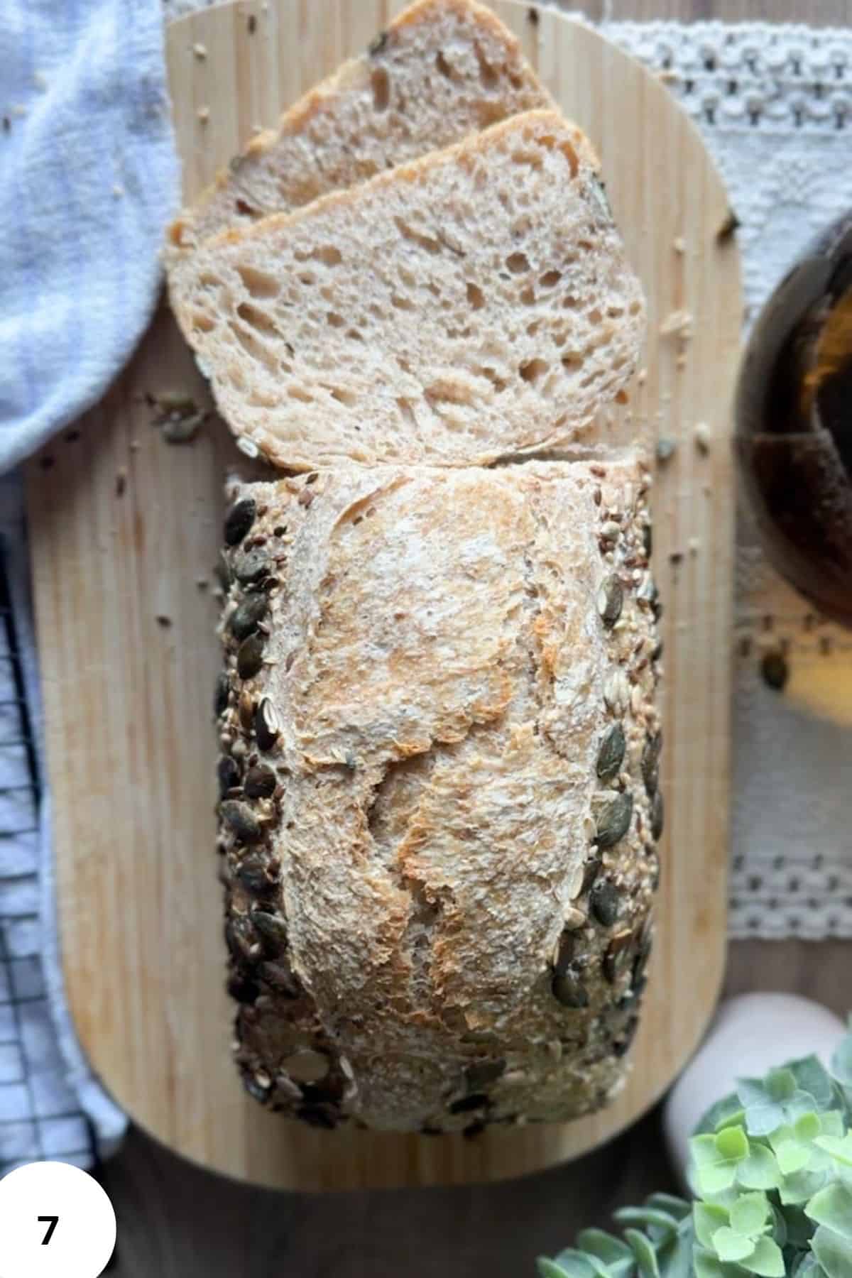 Healthy seed-crusted loaf of bread, sliced to show soft, airy interior.