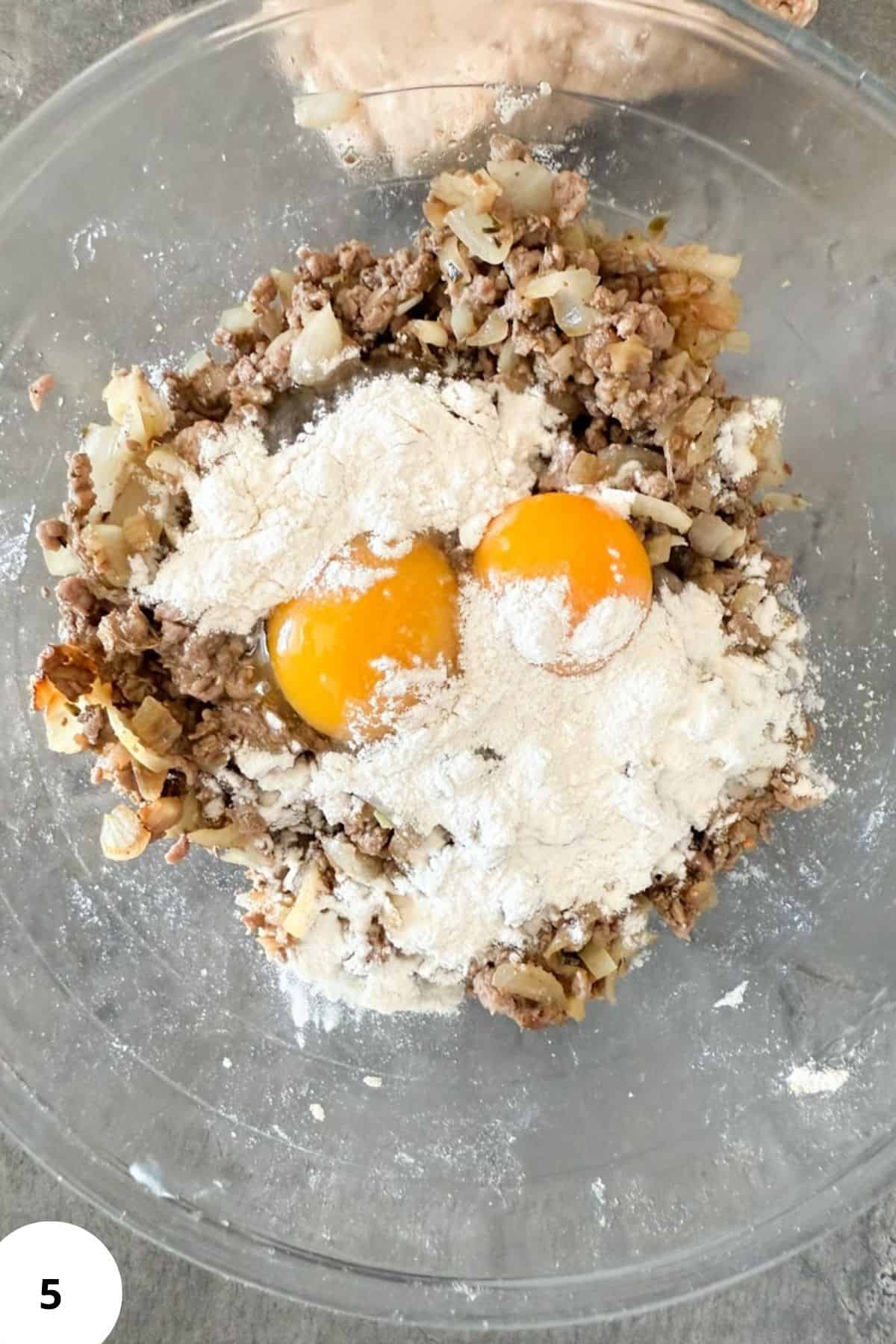 Close-up of ground meat, flour, eggs, and onions ready for baking or cooking.