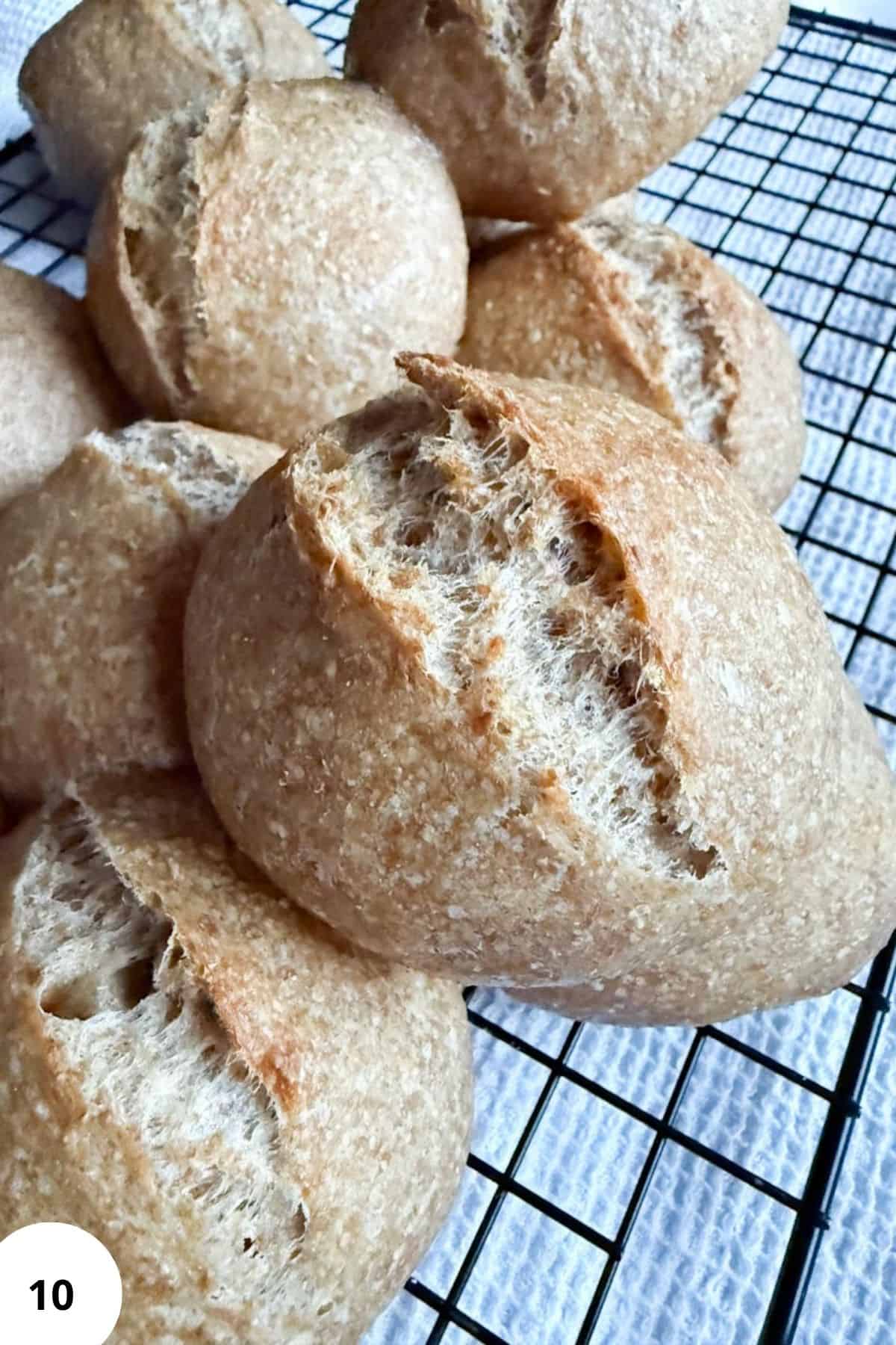 Freshly baked bread rolls with a crunchy crust on a cooling rack.