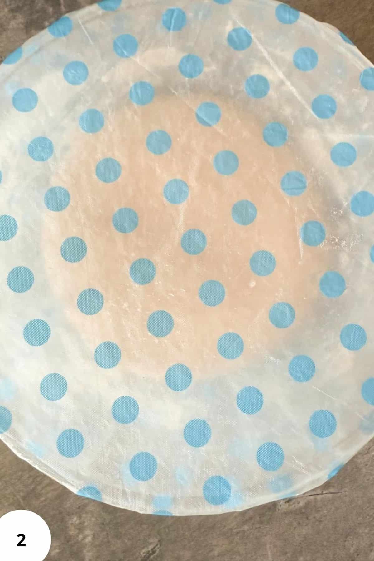 A bowl with dough covered with plastic.