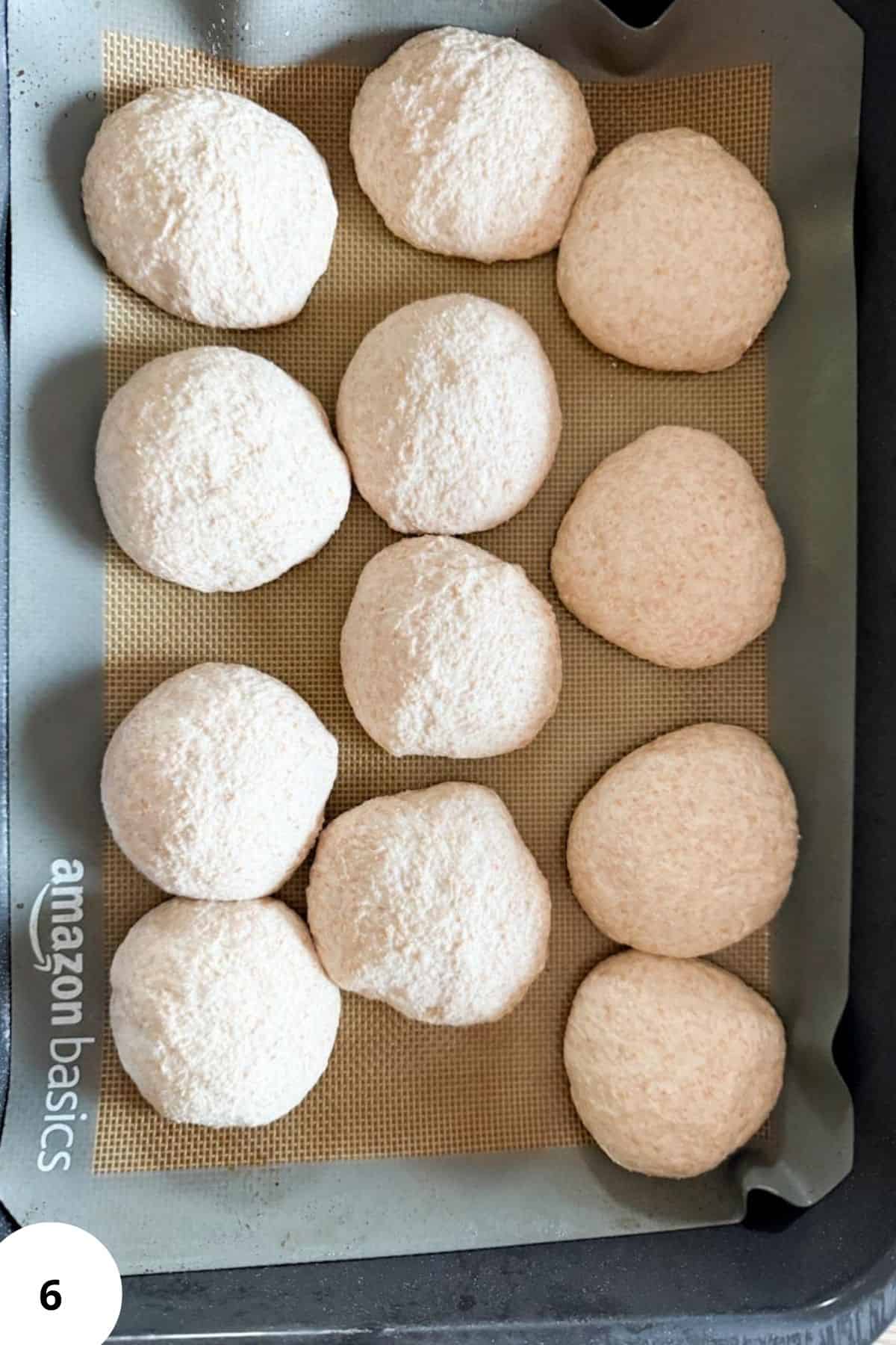 Freshly baked bread rolls on a baking sheet with parchment, homemade bread using freshly milled grains.