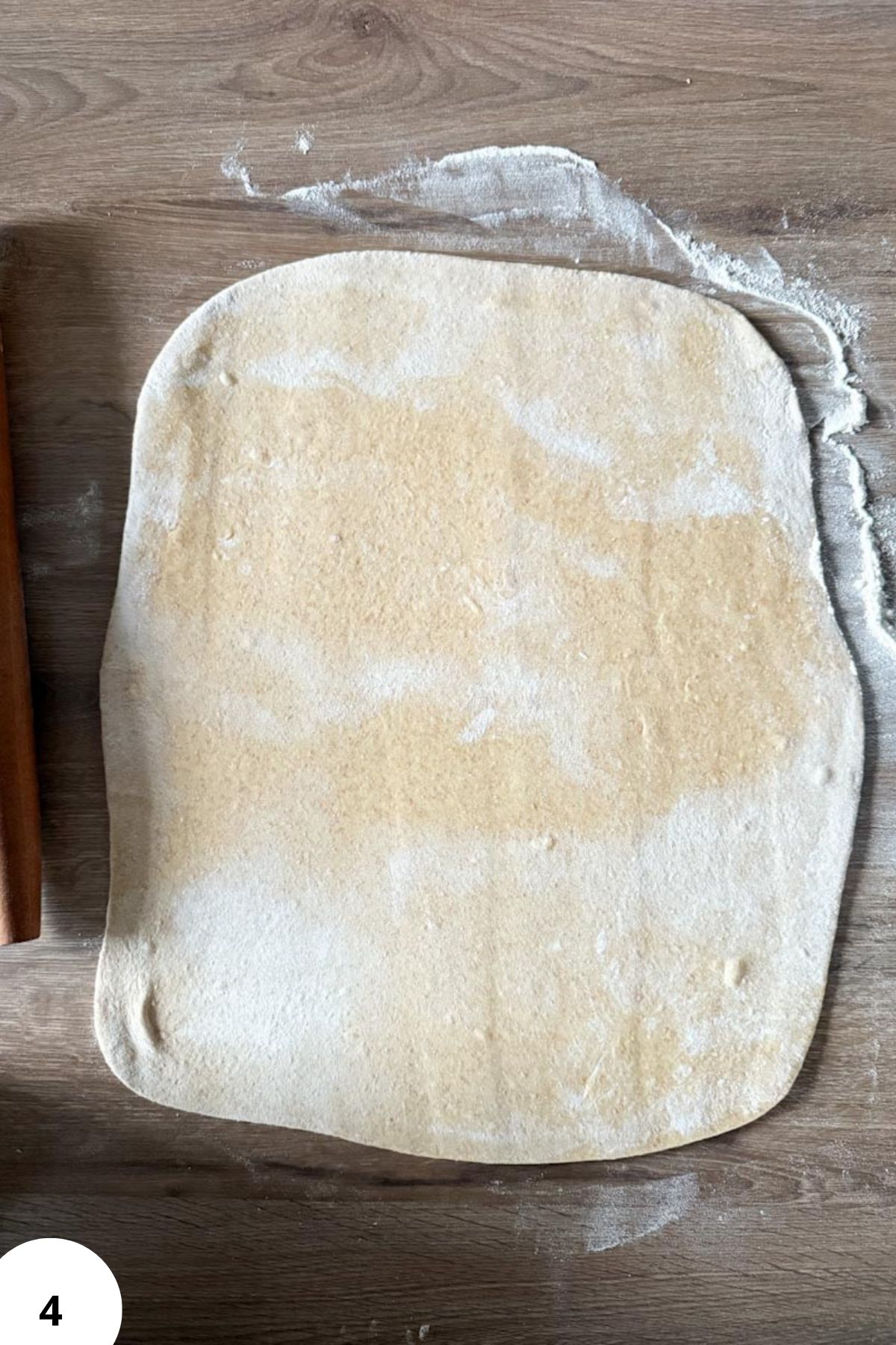 Alt text: Raw dough rolled out on a wooden surface with flour sprinkled around, for fresh milled recipes.