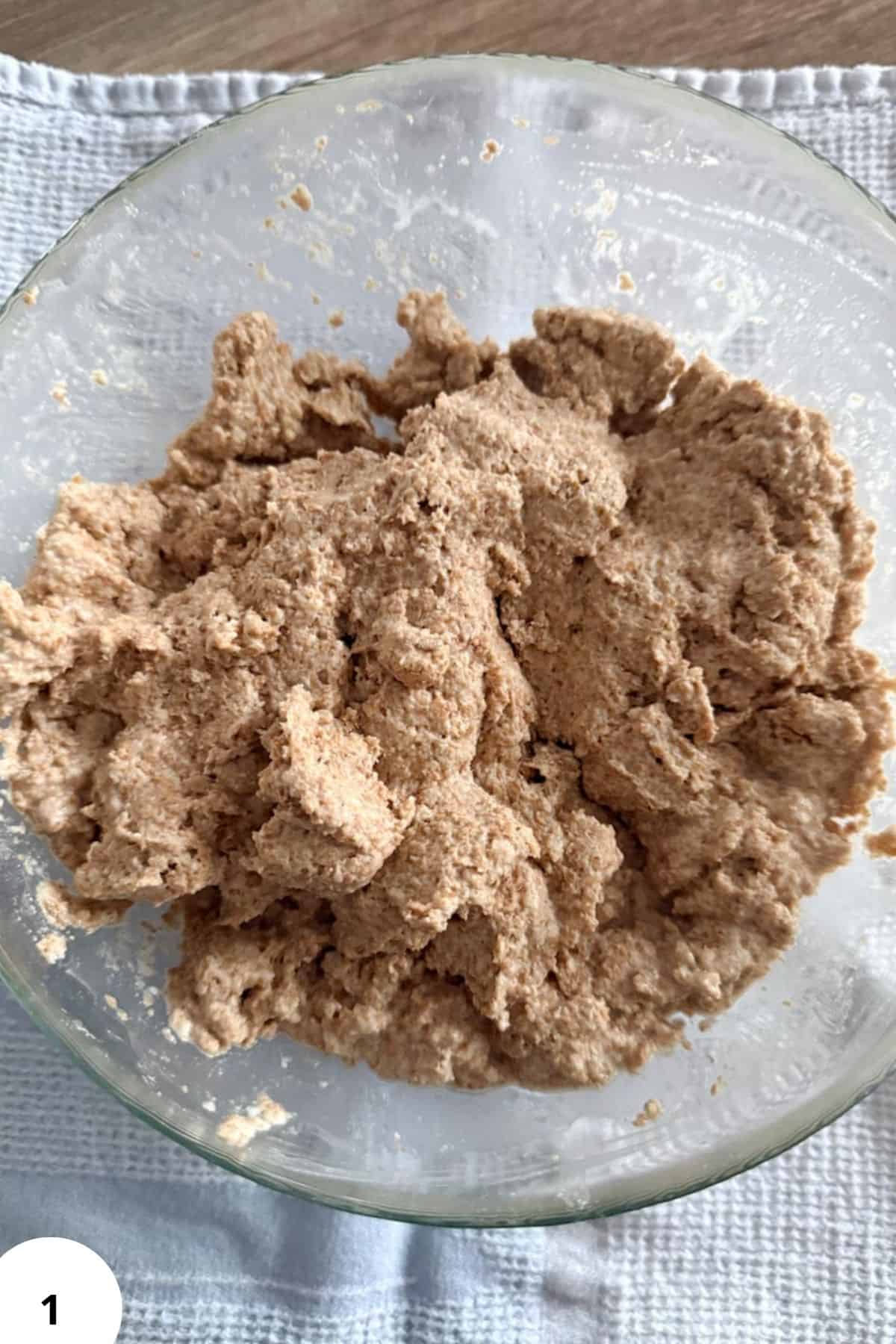 Natural millet flour dough in a glass bowl, healthy gluten-free baking ingredient.