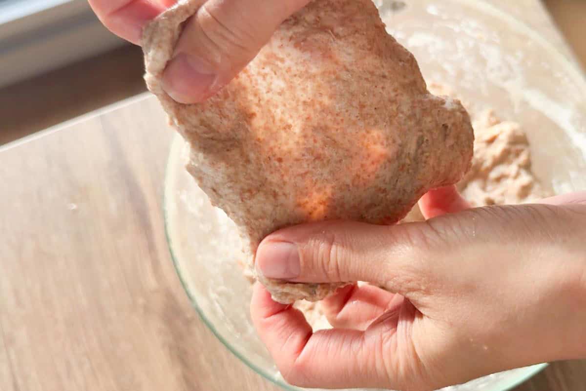 Hand holding dough for fresh baking bread, emphasizing healthy, whole grain recipes.