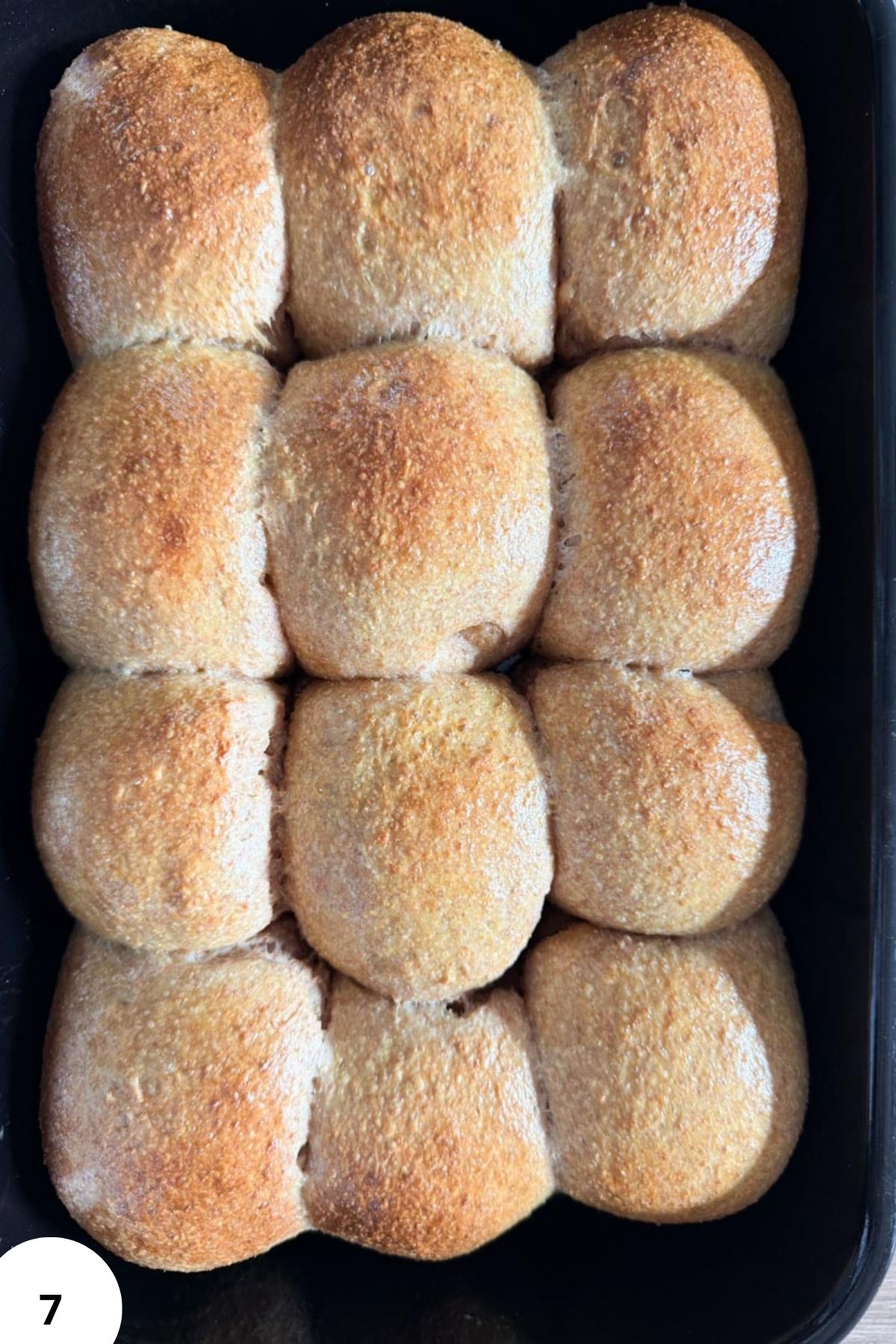 Golden, freshly baked bread rolls in a baking tray.