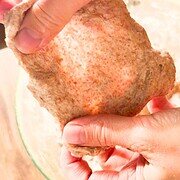 Close-up of a hand holding freshly milled grain bread, highlighting rustic texture and natural ingredients.
