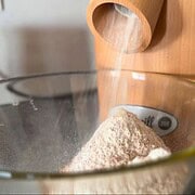Grain mill milling flour into a glass bowl.