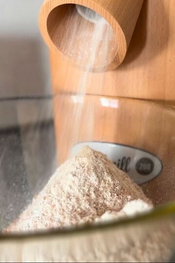 Grain mill milling flour into a glass bowl.