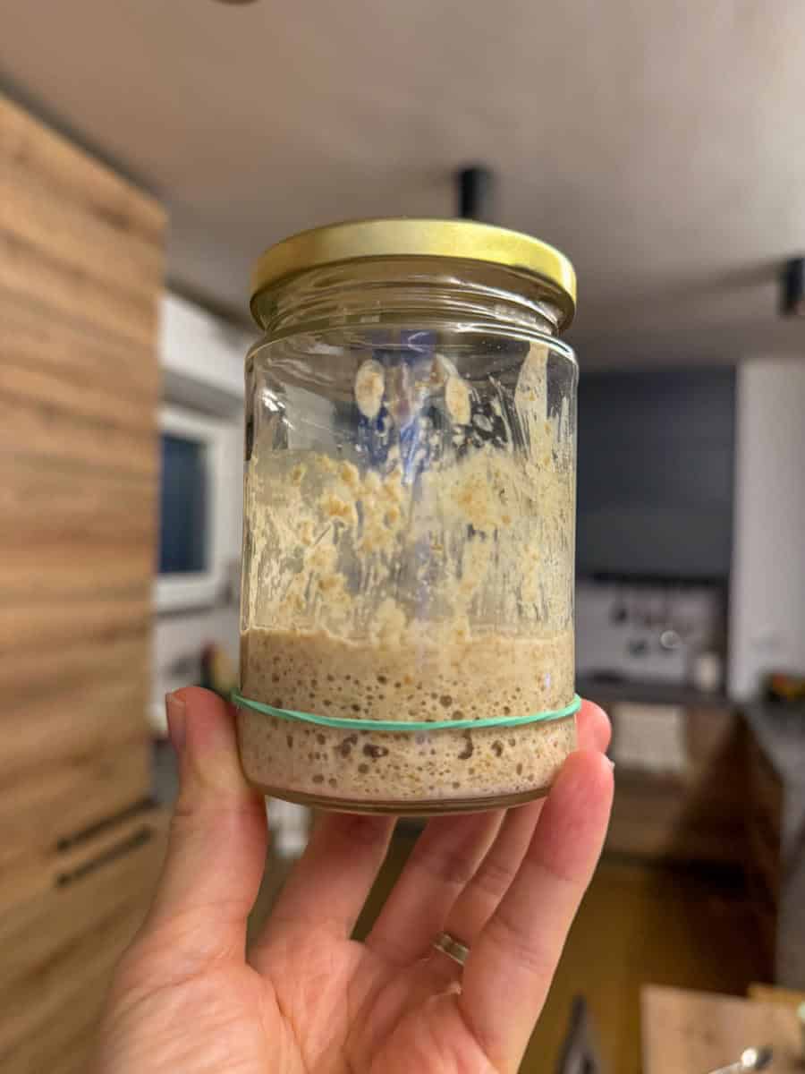 Homemade sourdough starter in a glass jar with fresh milled flour and water.