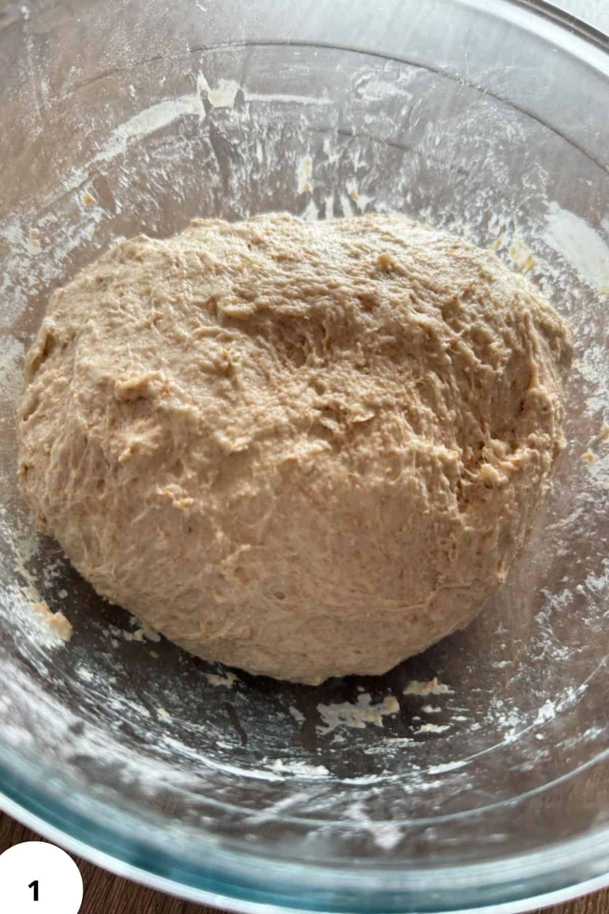 Dough made with freshly milled spelt flour in a glass mixing bowl.