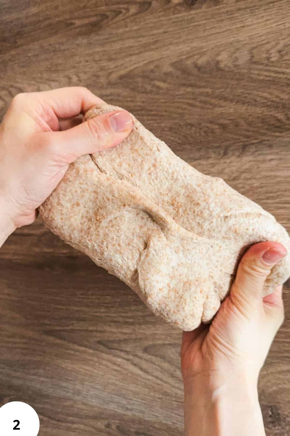 Hand holding fresh milled flour dough for sourdough pizza rolls.