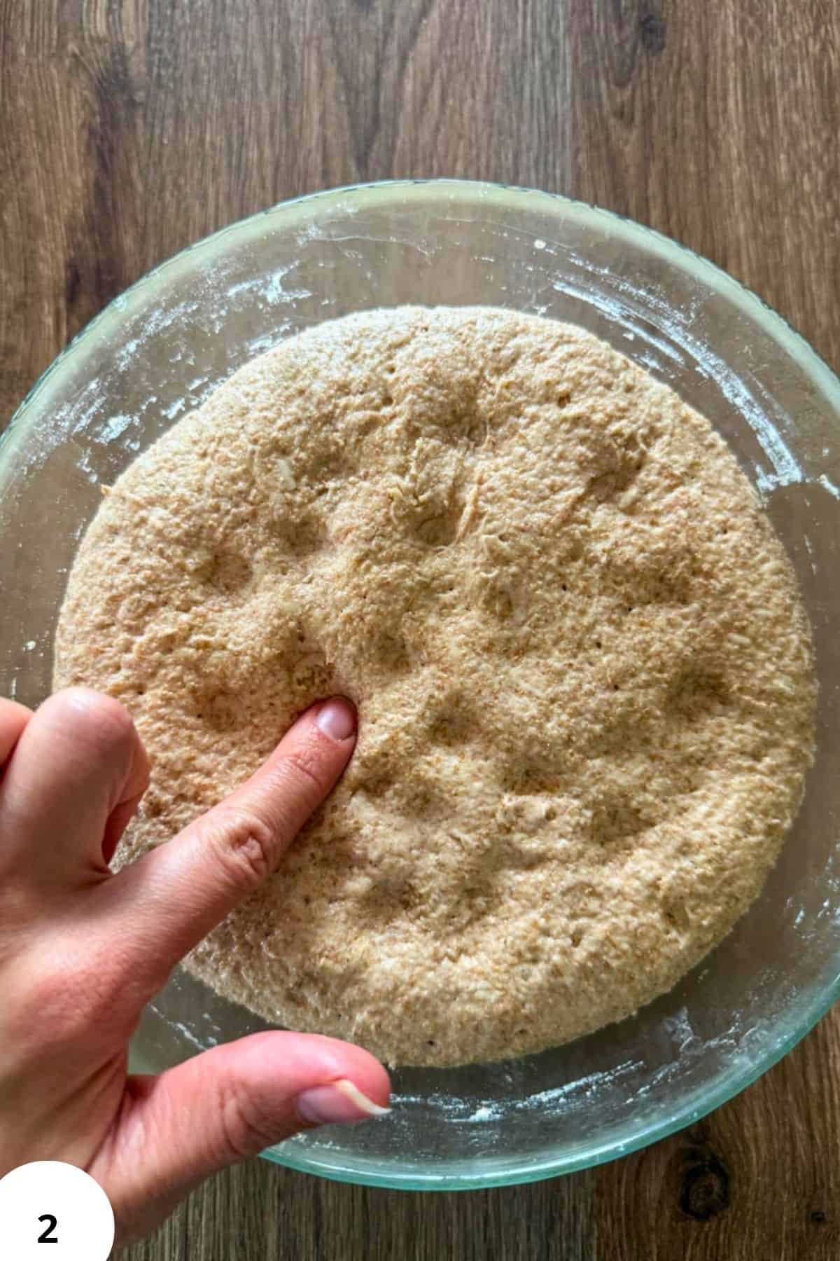 Freshly milled whole grain flour in a glass bowl on a wooden surface.
