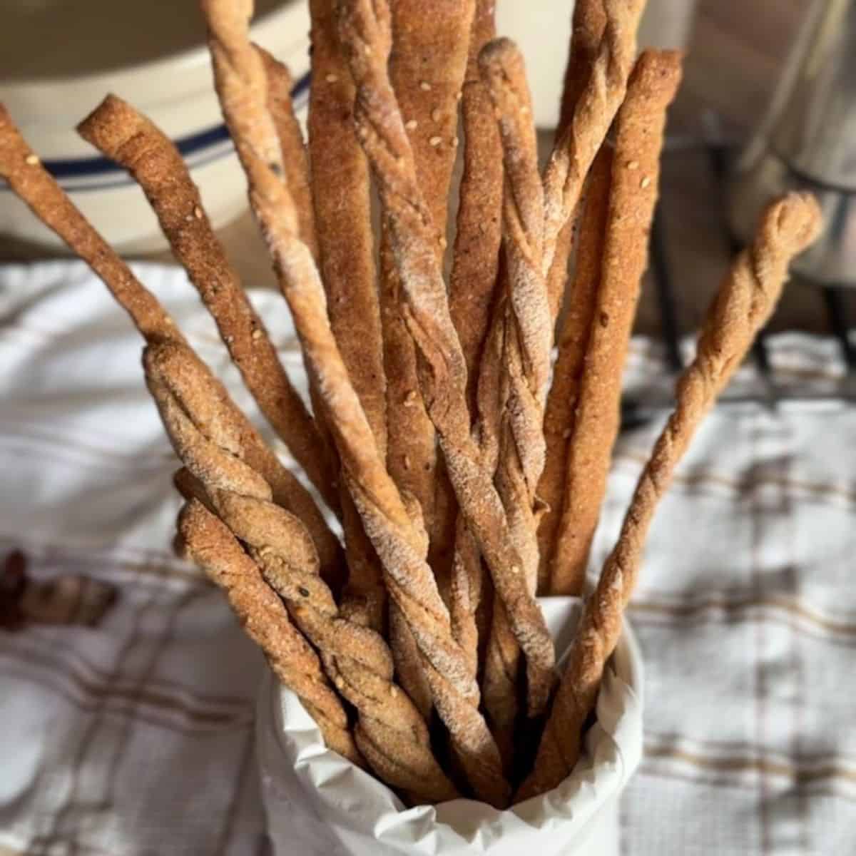 Freshly baked whole wheat breadsticks in a white paper cone.