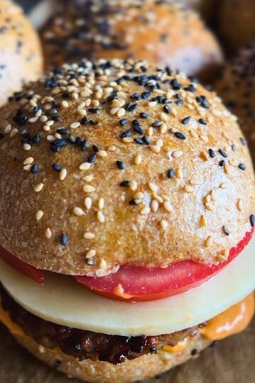 Close-up of a homemade burger slider with fresh ingredients and sesame seed bun.