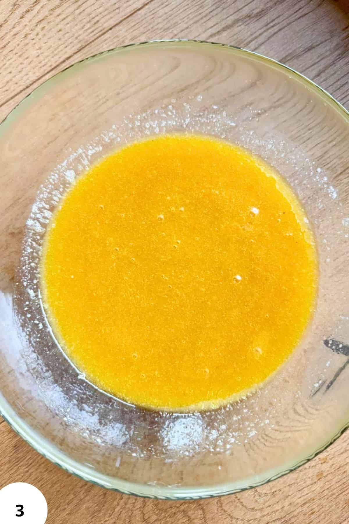 Close-up of yellow cookie dough in a glass bowl for soft and chewy cookies.