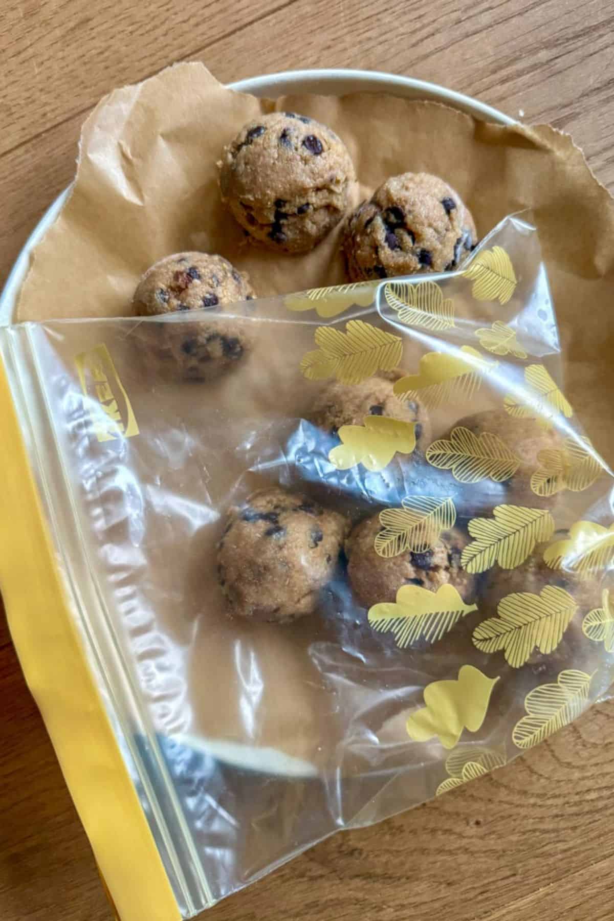 Freshly baked soft and chewy chocolate chip cookies in a bag on a wooden surface.