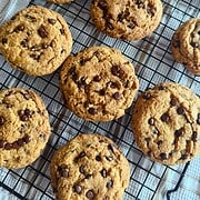 Freshly baked soft and chewy chocolate chip cookies on a cooling rack.