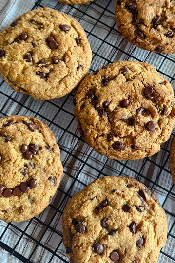 Freshly baked soft and chewy chocolate chip cookies on a cooling rack.