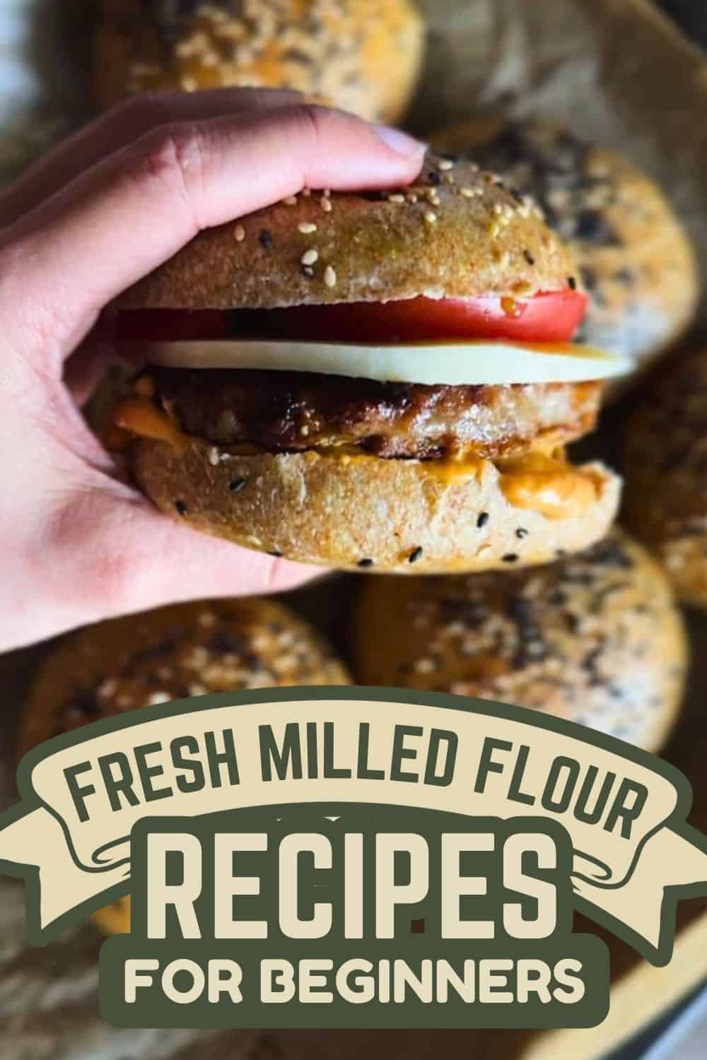 Hand holding a homemade burger with fresh milled flour bread and ingredients.