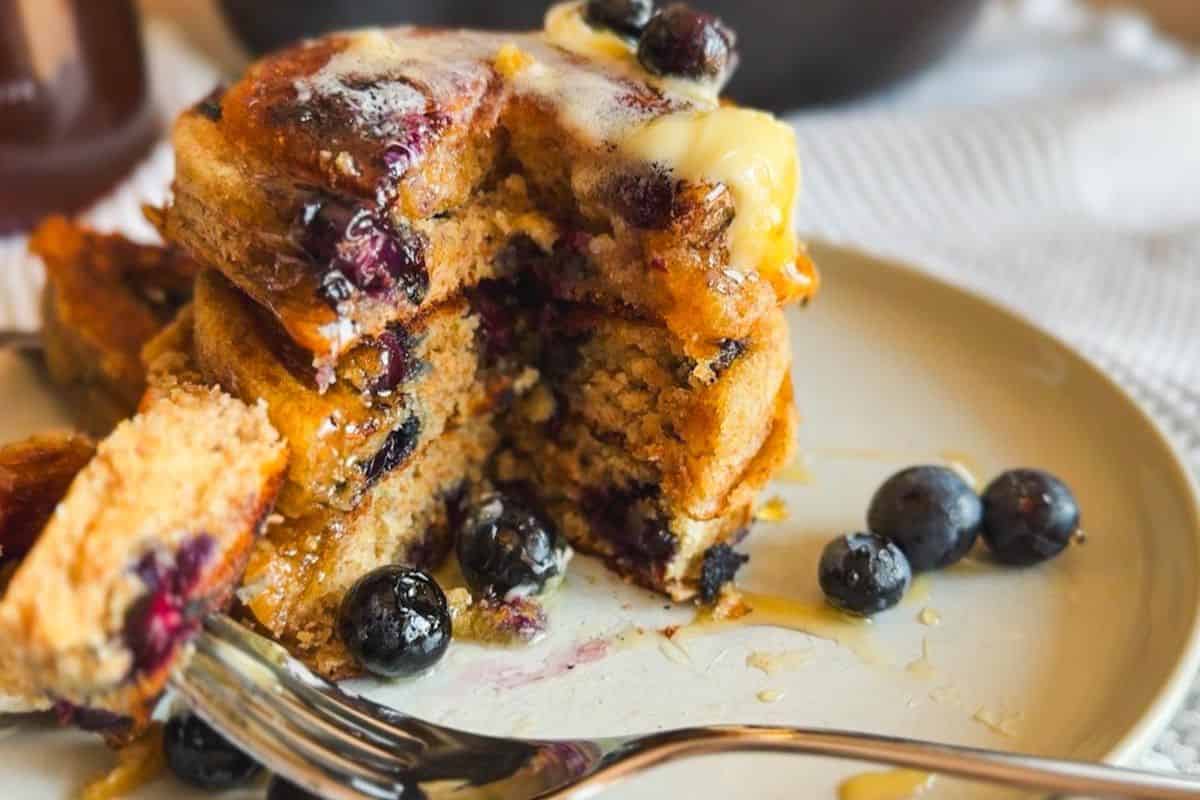 Close-up of blueberry sourdough pancakes with syrup and fresh blueberries.