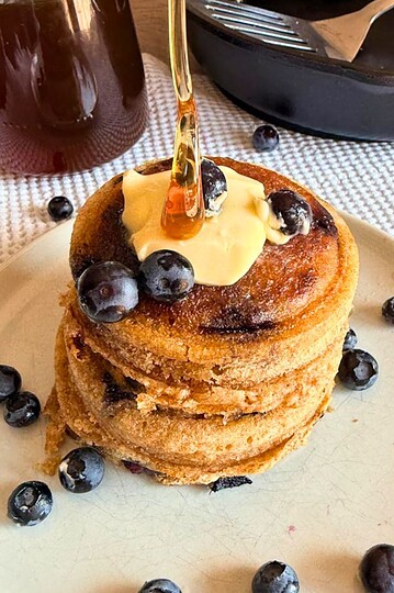 Stack of sourdough pancakes topped with blueberries and syrup.
