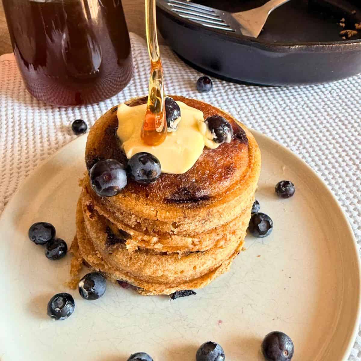 Stack of sourdough pancakes topped with blueberries and syrup.