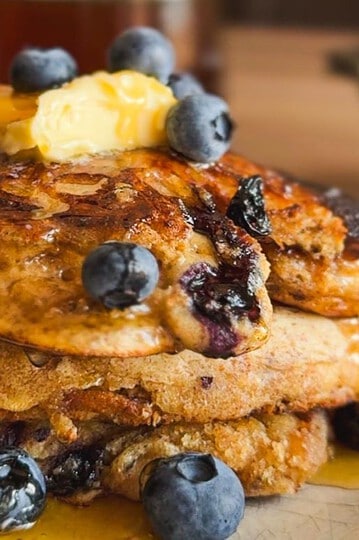 Stack of sourdough pancakes topped with blueberries and butter.