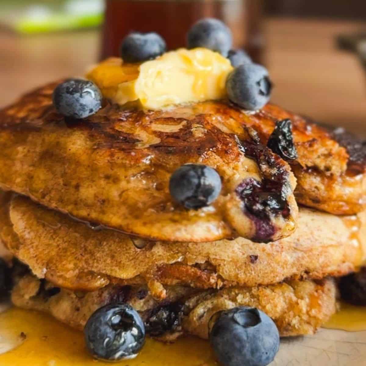 Stack of sourdough pancakes topped with blueberries and butter.