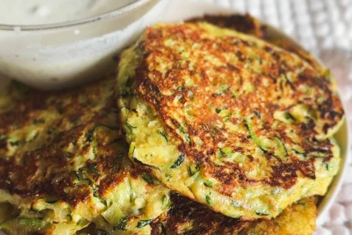 Golden zucchini fritters with herbs served with dipping sauce.