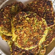 Close-up of golden zucchini fritters on a plate, crispy and freshly cooked.