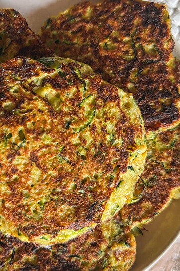 Close-up of golden zucchini fritters on a plate, crispy and freshly cooked.
