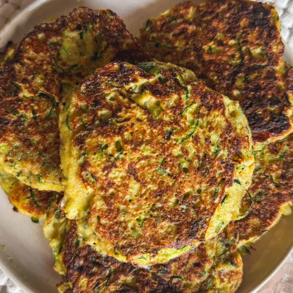 Close-up of golden zucchini fritters on a plate, crispy and freshly cooked.